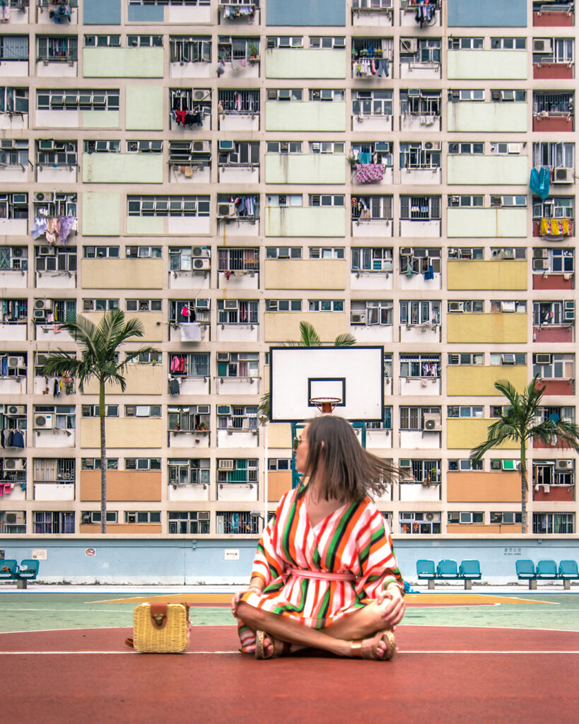 Marta sentada en la icónica cancha de baloncesto de colores de Choi Hung Estate en Hong Kong