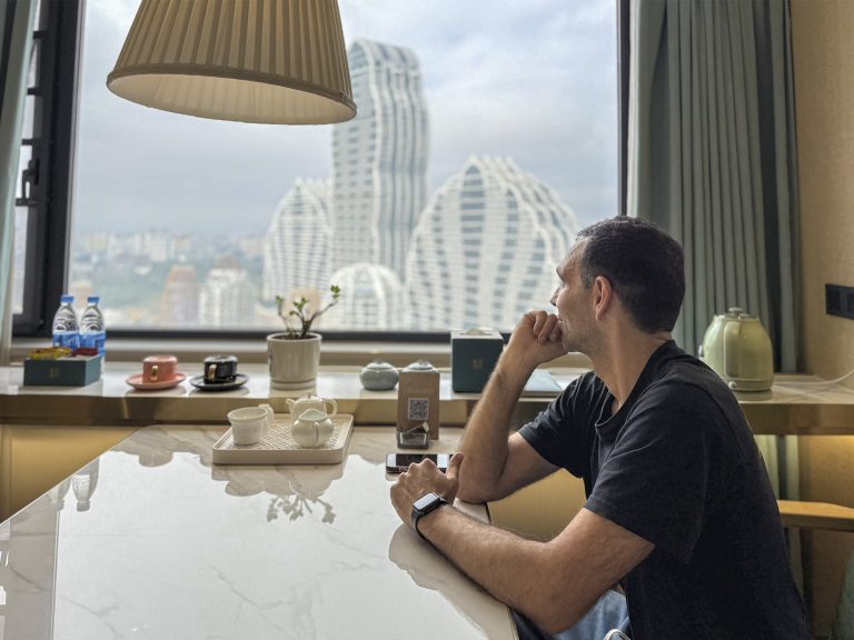 Habitación del Xishuangbanna Shanguan Sky View Hotel con diseño moderno, cama amplia y vistas a la ciudad de Jinghong desde la ventana.