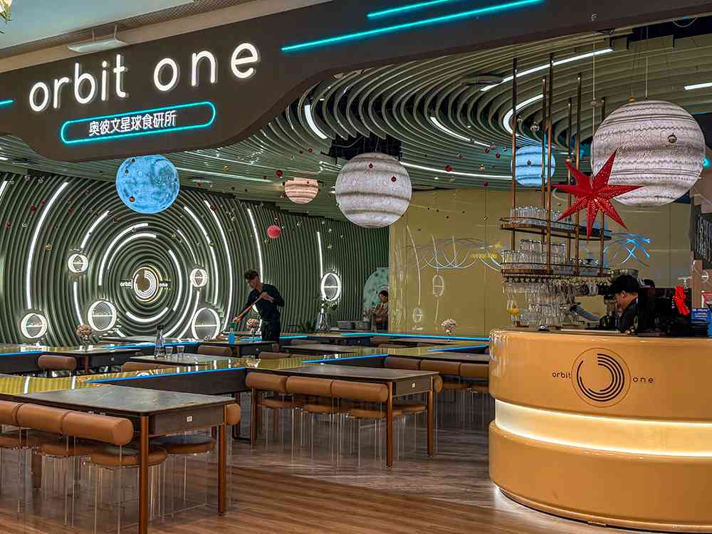 Comedor del restaurante Orbit One en Shenzhen, donde los platos llegan a la mesa como pequeños ovnis, una experiencia única.