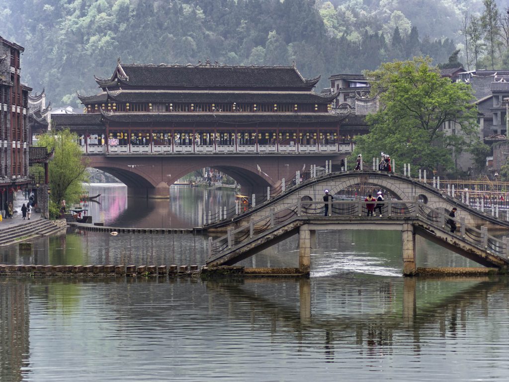 Puente de la Nube (Yunqiao) de tres arcos cubierto cruzando el río Tuojiang en Fenghuang. El puente de piedra con tejado de madera y pabellones se encuentra en la zona más tranquila del pueblo, lejos del centro turístico