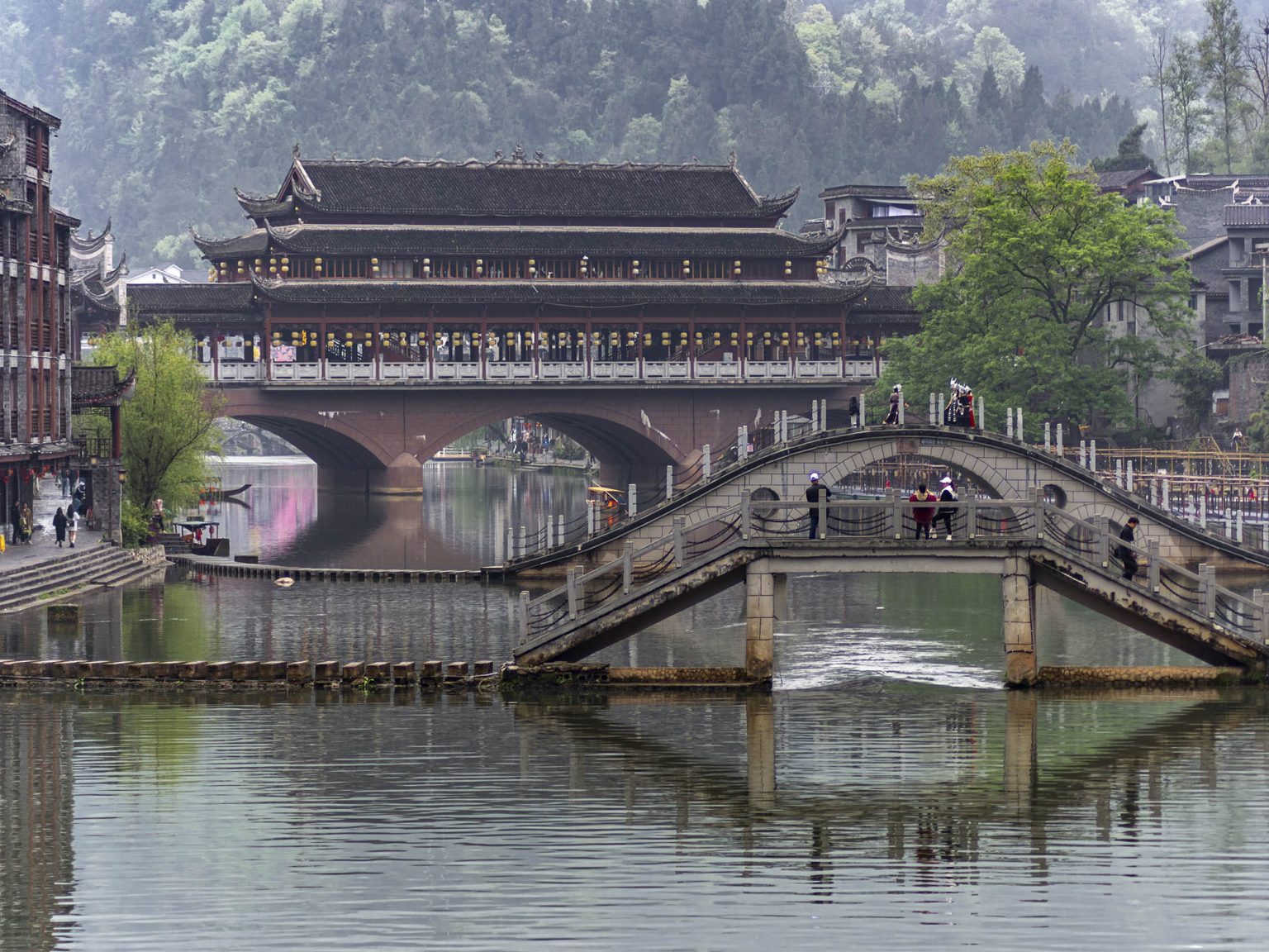Puente de la Nube (Yunqiao) de tres arcos cubierto cruzando el río Tuojiang en Fenghuang. El puente de piedra con tejado de madera y pabellones se encuentra en la zona más tranquila del pueblo, lejos del centro turístico