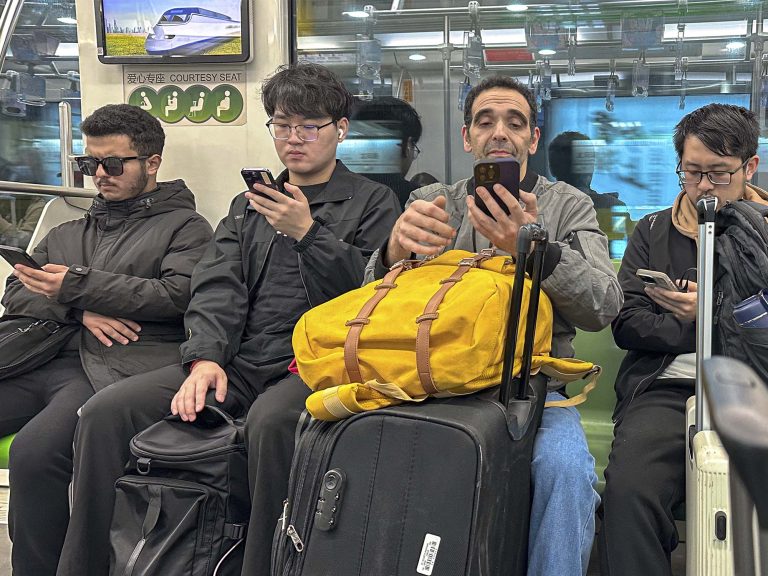 Javi sentado entre ciudadanos chinos en el metro de Pekín, todos mirando sus móviles