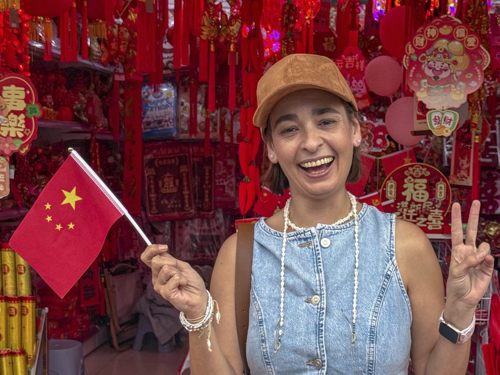 Viajero español con bandera de España haciendo señal de victoria en China, viaje sin visado 2026