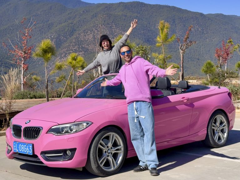 Dos personas posando junto a un BMW rosa durante un viaje por la provincia de Yunnan, China