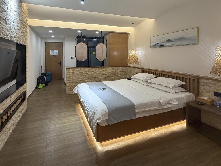 Habitación amplia y luminosa en el Guanshan Yaju Hotel de Dujiangyan, con cama queen de látex puro, ventana con vistas a la ciudad, colchón de látex, escritorio y detalles decorativos de estilo tradicional chino.