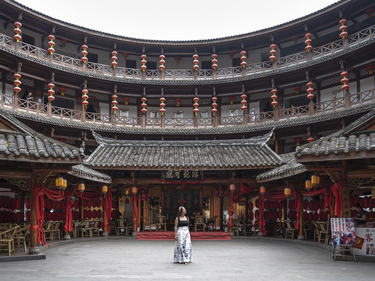 Vista exterior de la réplica del tulou Hakka en Luodai Ancient Town, Chengdu, un edificio circular de cuatro plantas con muros de tierra y tejados de estilo tradicional, inspirado en la película "El viaje de Chihiro".