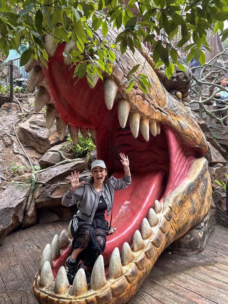 Marta metida en la boca de un dinosaurio animatrónico en Gulong Gorge, Qingyuan, China