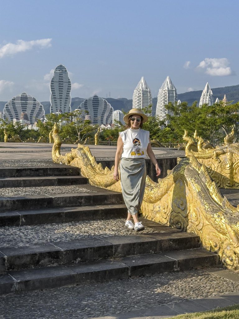 Marta caminando por una calle de Jinghong con los rascacielos de la ciudad al fondo, Xishuangbanna, China
