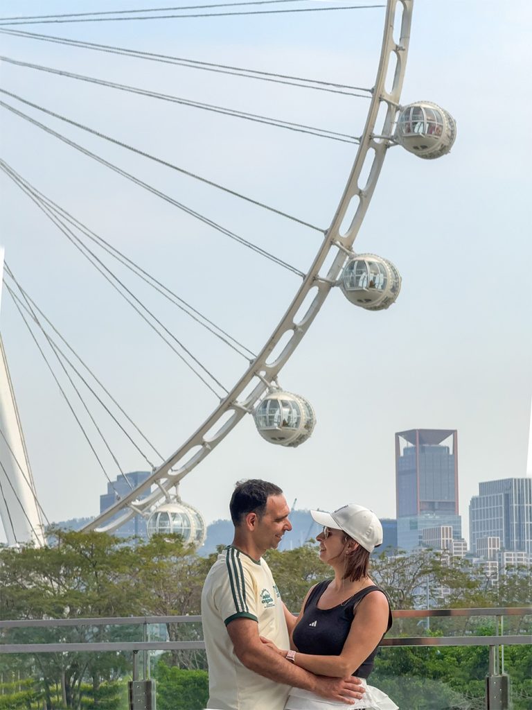 Nosotros posando con la noria Ojo de la Bahía de Happy Harbour al fondo, Shenzhen, China