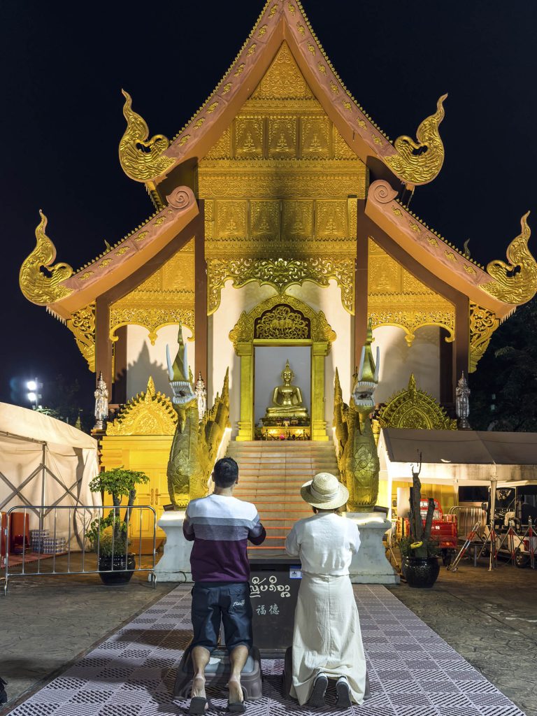 Nosotros rezando de rodillas en el interior de un templo budista cerca del mercado nocturno de Jinghong, Xishuangbanna, China