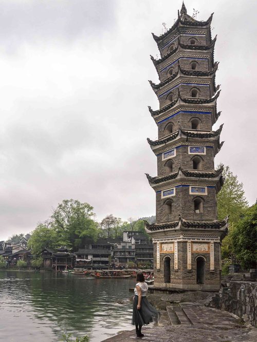 Pagoda Wanming (Wanming Ta) de siete pisos y forma hexagonal iluminada por la noche reflejándose en el río Tuojiang en Fenghuang, Hunan. La torre de ladrillo reconstruida en 1985 por el artista Huang Yongyu es uno de los íconos más fotografiados del pueblo del Fénix