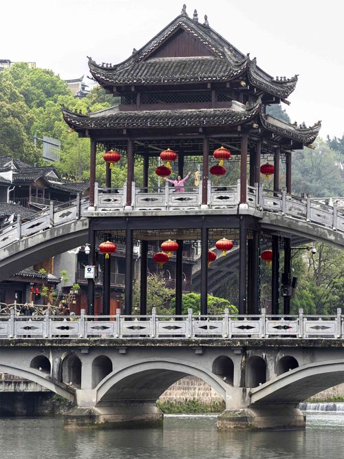 Puente de Nieve (Xueqiao) de madera cubierto con dos niveles y un pabellón central mirador, cruzando el río Tuojiang en Fenghuang. El puente diseñado por el artista Huang Yongyu es uno de los más fotogénicos del pueblo del Fénix