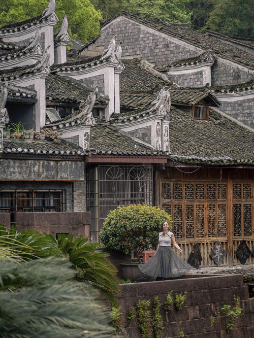 Vista aérea de los tejados de tejas negras superpuestos y aleros curvos (flying eaves) de las casas tradicionales de Fenghuang. Los característicos techos de las viviendas Miao y Tujia se extienden formando un mosaico de curvas y sombras junto al río Tuojiang