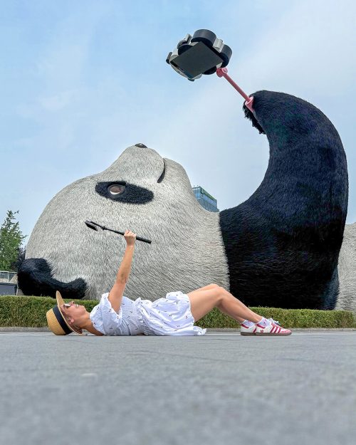 Escultura gigante del Selfie Panda de 26 metros de largo en la plaza Yangtianwo de Dujiangyan, con el panda recostado sobre el lomo sosteniendo un palo selfie con un teléfono móvil.