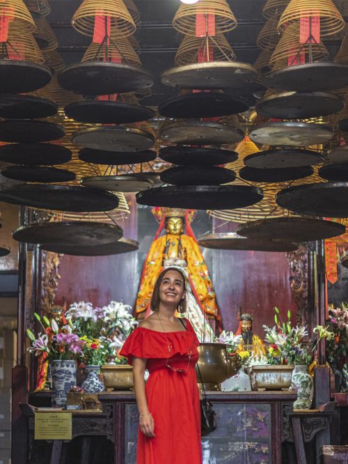 Chica bajo muchas espirales de incienso dentro de un templo en Hong Kong